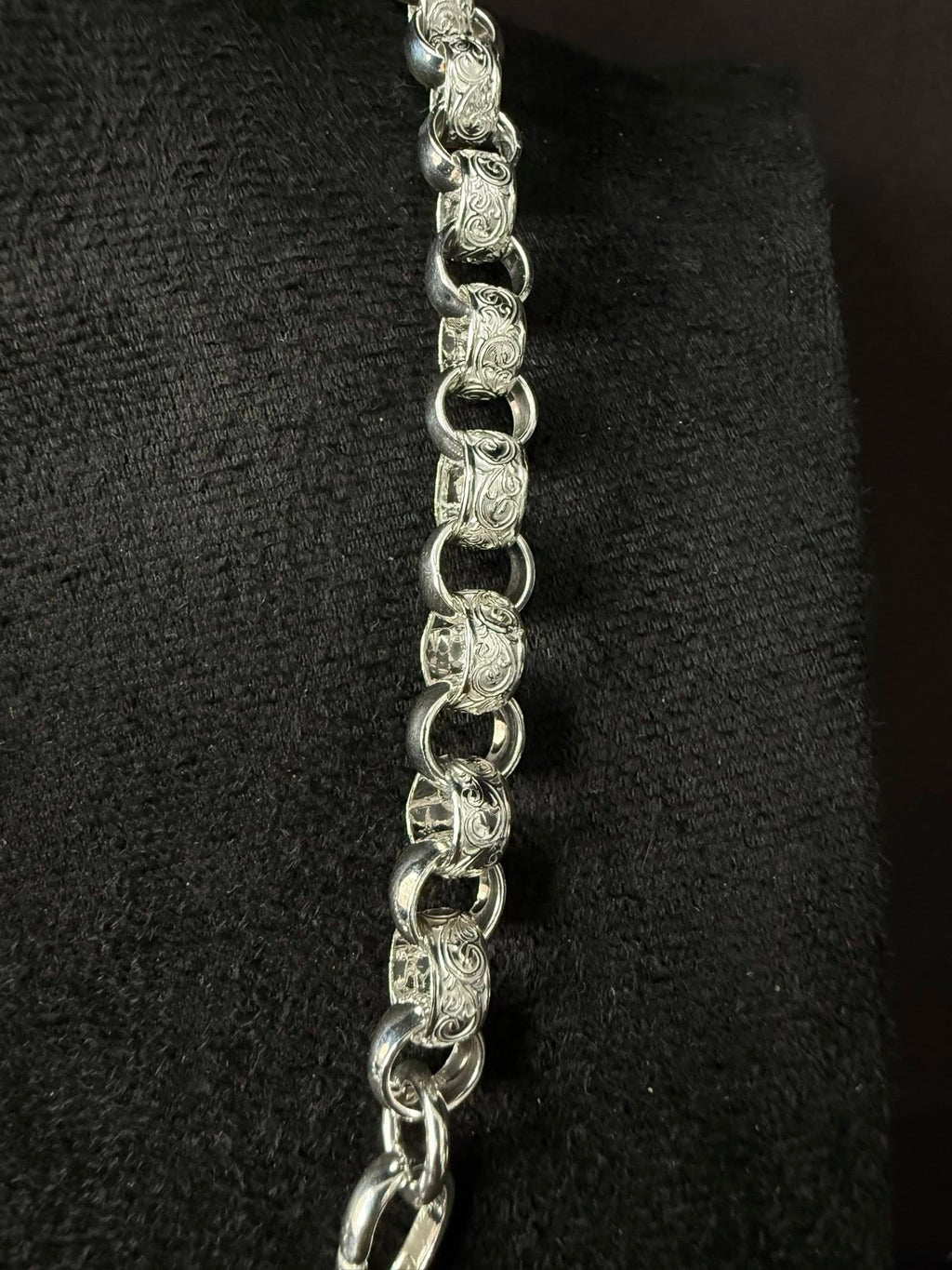 Silver chain necklace on a black textured background